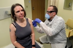 FILE - A pharmacist gives Jennifer Haller, left, the first shot in the first-stage safety study clinical trial of a potential vaccine for COVID-19, the disease caused by the new coronavirus, Monday, March 16, 2020.