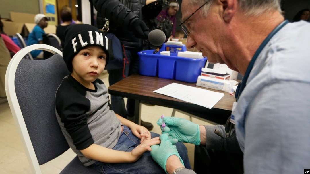 FILE - A nurse draws a blood sample from an elementary school student in Flint, Michigan, Jan. 26, 2016. Students at the school were being tested for lead after the metal was found in the city's drinking water.
