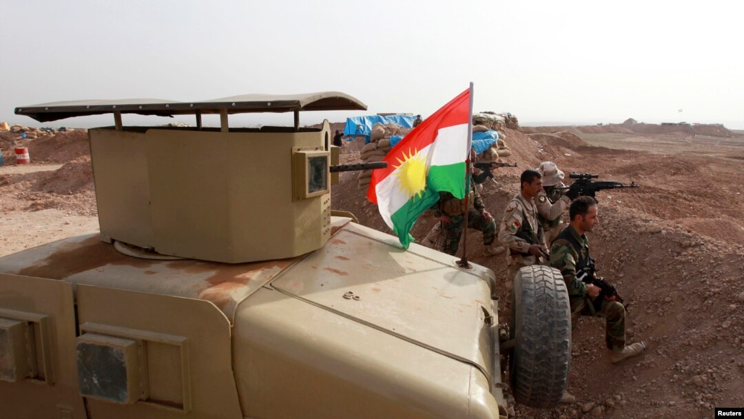 A Kurdish flag is seen next to Peshmerga fighters taking position with their weapons on the frontline against the Islamic State, on the outskirts of Mosul, Iraq, Jan. 26, 2015.