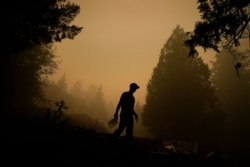 Aaron Cleys camina con un galón de agua tras combatir el fuego en una casa que fue destruida por el incendio Riverside, el viernes 11 de septiembre de 2020, en Estacada, Oregón.