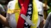 Una enfermera usa una bufanda con colores de la bandera venezolana, y un recorte que representa una jeringuilla, durante una protesta para exigir una distribución más equitativa y rápida de las vacunas, en Caracas, el 17 de abril de 2021. 
