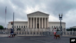 La gente pasea a los perros frente a la valla erigida alrededor de la Corte Suprema de los Estados Unidos en Washington, el 23 de junio de 2022.
