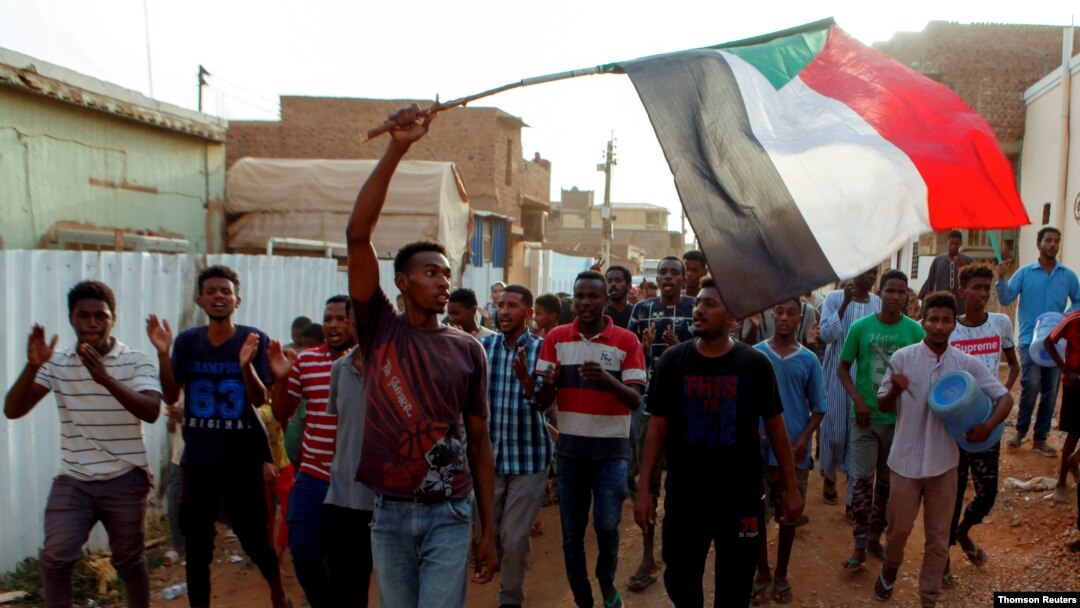 FILE - Sudanese protesters chant slogans and wave their national flag as they demonstrate against the ruling military council, in Khartoum, June 27, 2019. 