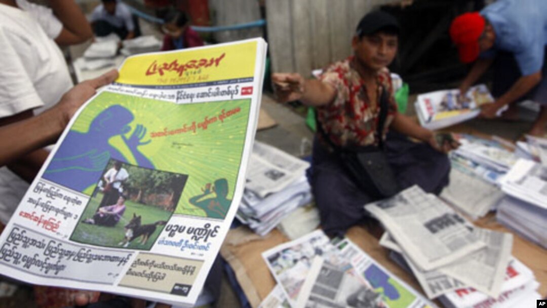 A man at a market in Rangoon, shows a People's Age private journal featuring an article written by Burma's pro-democracy leader Aung San Suu Kyi, September 6, 2011.