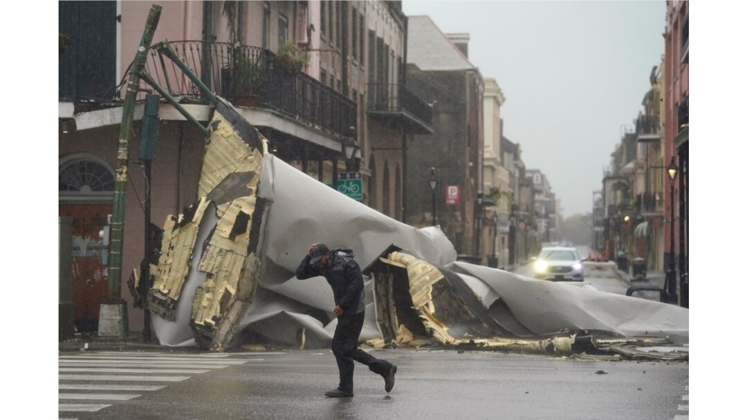 Un hombre pasa por una sección del techo que se desprendió de un edificio en el Barrio Francés por los vientos del huracán Ida, el domingo 29 de agosto de 2021, en Nueva Orleans.