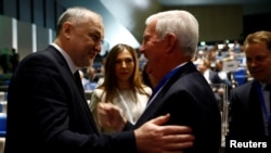 FILE - Craig Reedie, head of the World Anti-Doping Agency (WADA), right, welcomes Yuri Ganus, Russian Anti-Doping Agency (RUSADA) director general, at the WADA Symposium in Ecublens, near Lausanne, Switzerland, March 21, 2018.