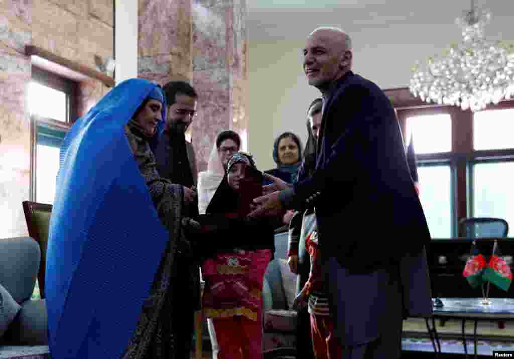 Sharbat Gula (L), the green-eyed "Afghan Girl" whose 1985 photo in National Geographic became a symbol of her country's wars, receives a key to an apartment from Afghanistan's President Ashraf Ghani, after she arrived in Kabul. Pakistan officials said Gula was deported to her native country.