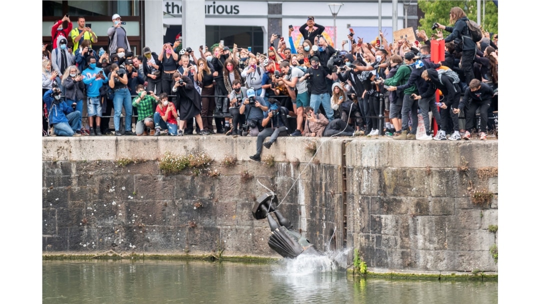 FILE - The statue of 17th century slave trader Edward Colston falls into the water after protesters pulled it down during a protest against racial inequality, in Bristol, Britain, June 7, 2020.