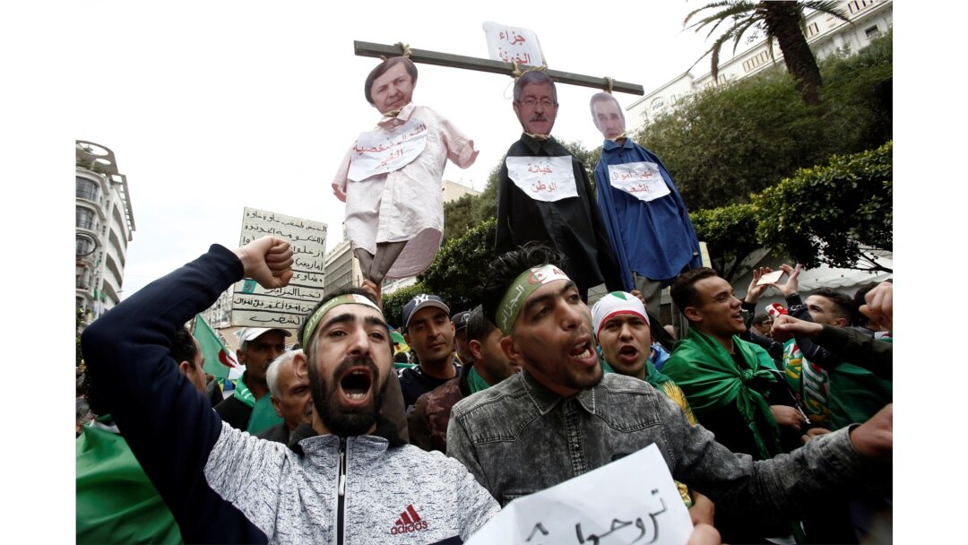 FILE - People carry a mock hangman with faces of businessman Ali Haddad, former Prime Minister Ahmed Ouyahia, and Said Bouteflika, brother of the former president, during a protest against the political structure, in Algiers, Algeria, April 5, 2019.