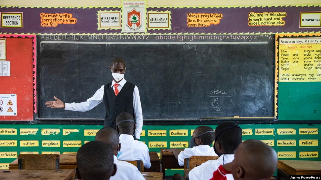 A teacher welcomes back students during a classroom lesson on day one of re-opening schools in Kampala, Uganda on Jan. 10, 2022.