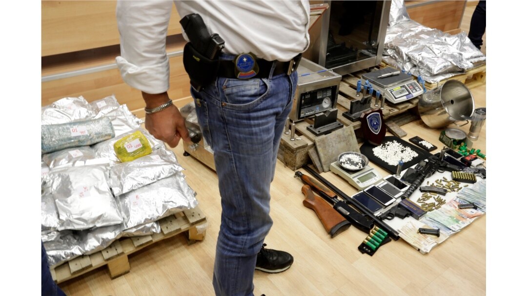 FILE - A member of Finance Crimes Squad stands in front of confiscated items after a news conference in Athens, , March 6, 2017.
