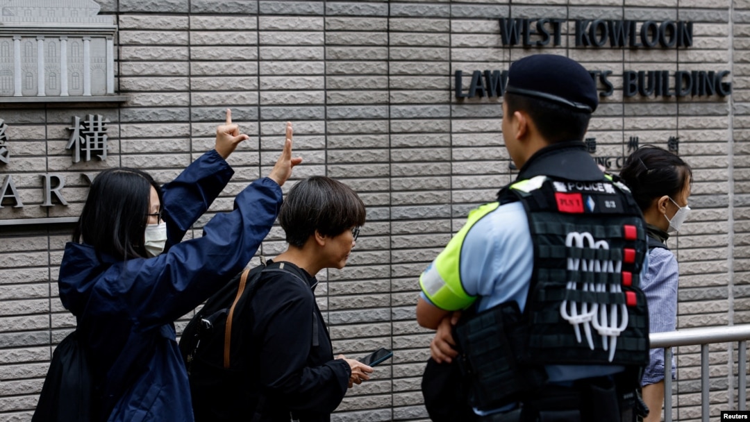 一名女子在香港西九龍裁判法院外等待根據國家安全法受到指控的47名民主活動人士的判決時打出支持的手勢。 （2024年5月30日）