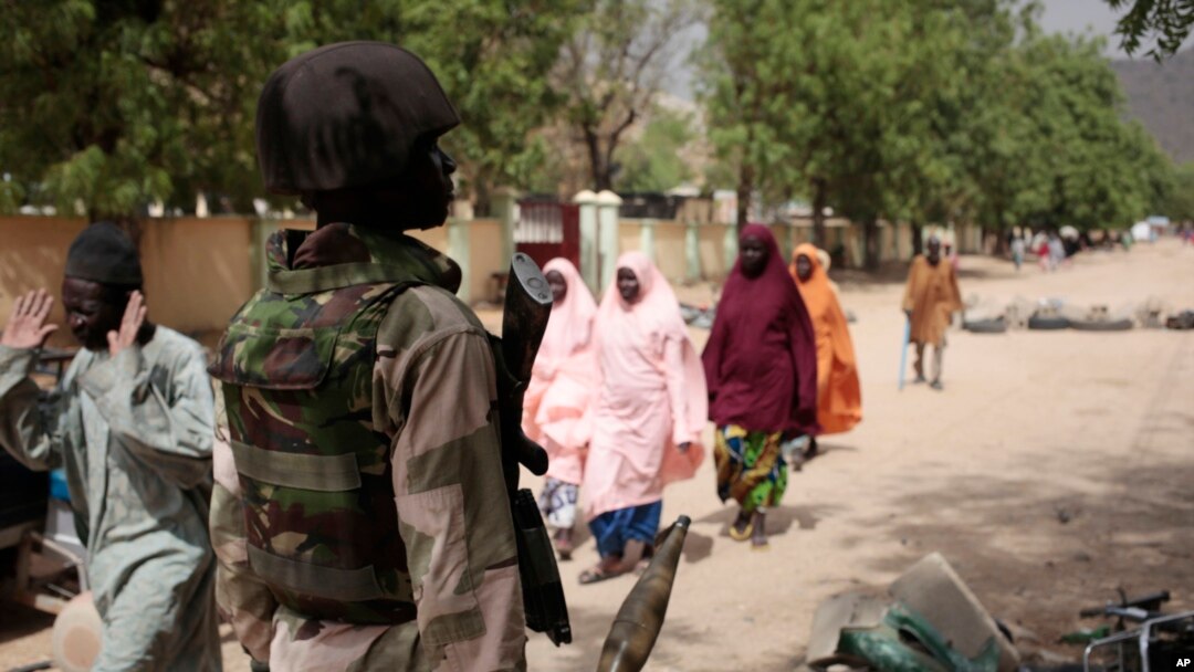 En esta foto tomada el 8 de abril, de 2015, civiles pasan frente a un punto de control del ejército nigeriano en Gwoza, Nigeria, un pueblo recientemente liberado de Boko Haram.