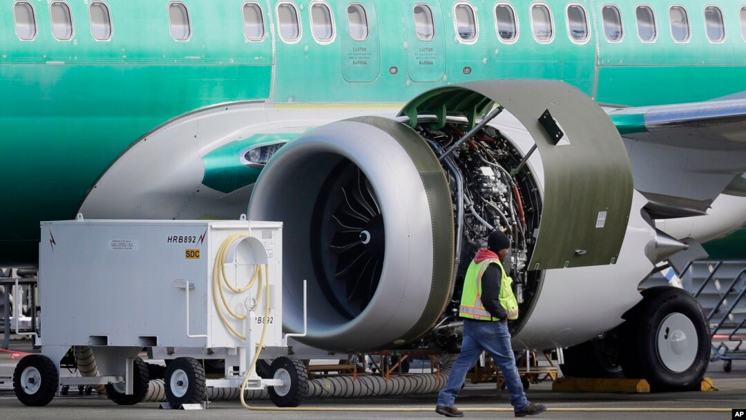A worker walks past an engine on a Boeing 737 MAX 8 airplane being built for American Airlines at Boeing Co.'s Renton assembly plant, March 13, 2019, in Renton, Wash.