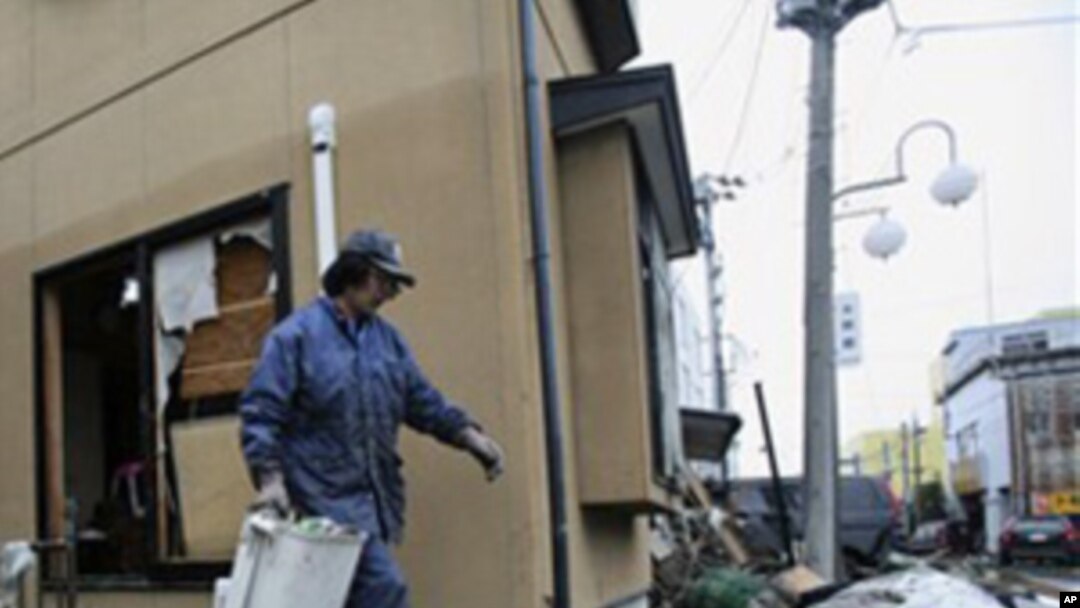 A resident cleans up tsunami debris in his destroyed house Tuesday, March 15, 2011, in Soma city, Fukushima prefecture, Japan, four days after a massive earthquake and tsunami struck the country's north east coast. (AP Photo/Wally Santana)