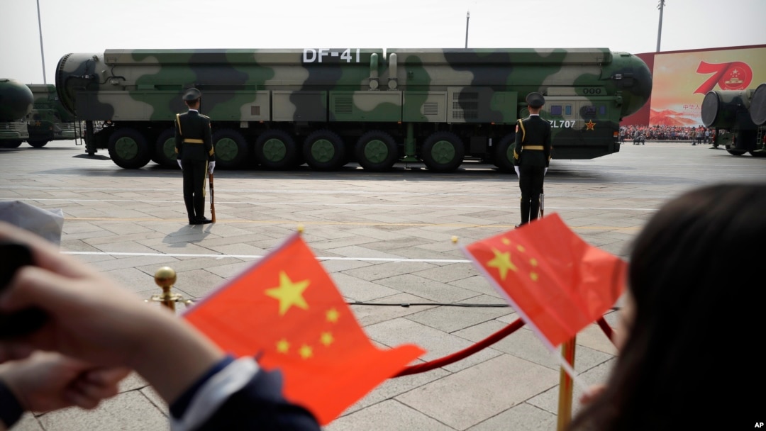 FILE - Onlookers wave Chinese flags as military vehicles carrying DF-41 ballistic missiles pass during a parade in Beijing, China, Oct. 1, 2019.