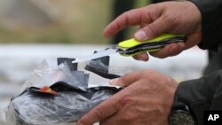 FILE - An official opens a package of seized cocaine in Colombia, Feb. 24, 2015. 