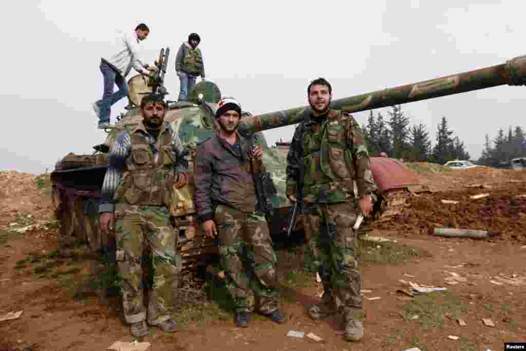 Free Syrian Army fighters pose with a tank after capturing the Military Infantry School following heavy clashes, Aleppo, Syria, December 16, 2012.