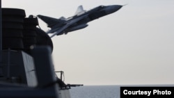 FILE - A Russian aircraft makes a flyover pass near the USS Donald Cook in the Baltic Sea, April 12, 2016.
