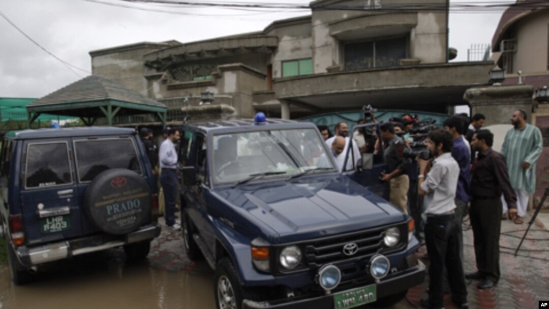 Pakistani media follow a senior police officer at outside the house of a abducted American citizen in Lahore, Pakistan, August 13, 2011