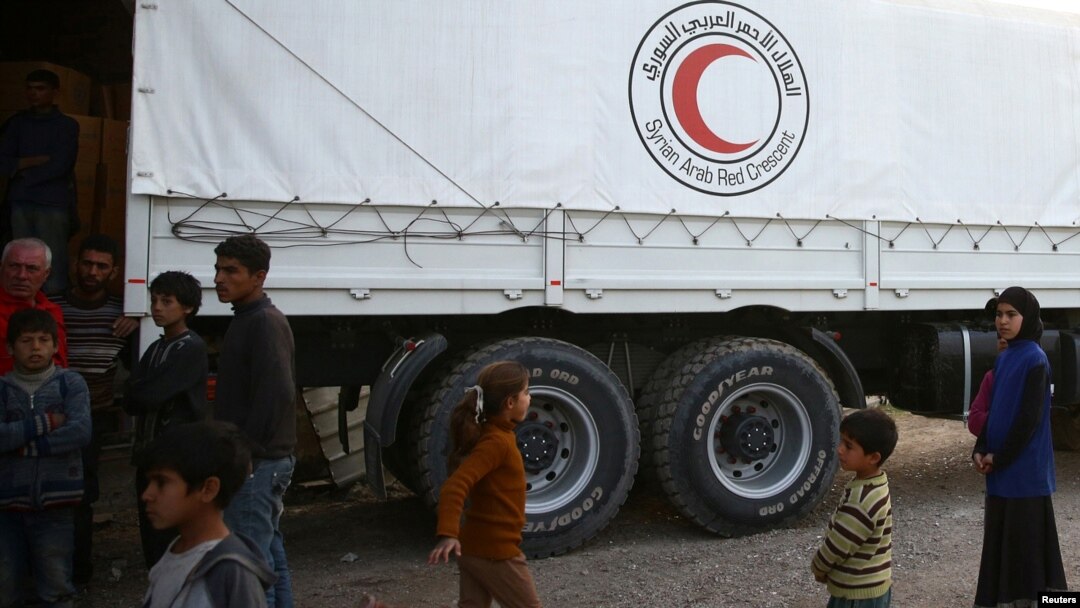 People stand next to Syrian Arab Red Crescent truck in the town of Nashabiyeh, eastern Ghouta in Syria, Nov. 28, 2017. 