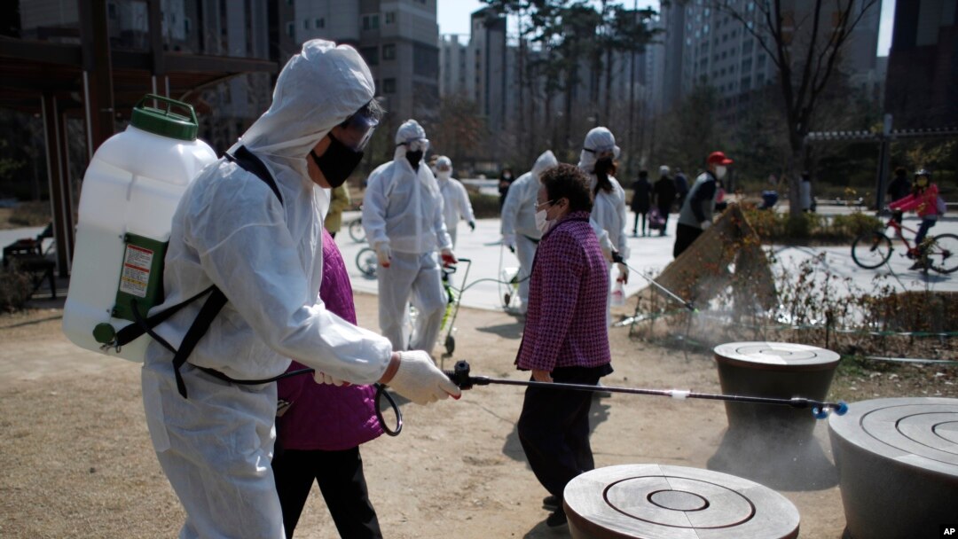 Members of a local residents group wear protective gear as they disinfect a local park as a precaution against the new coronavirus in Seoul, South Korea, Monday, March 23, 2020. 