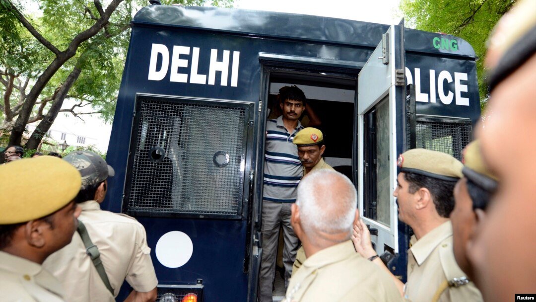 FILE - A man is escorted out of a police van outside a court in New Delhi.
