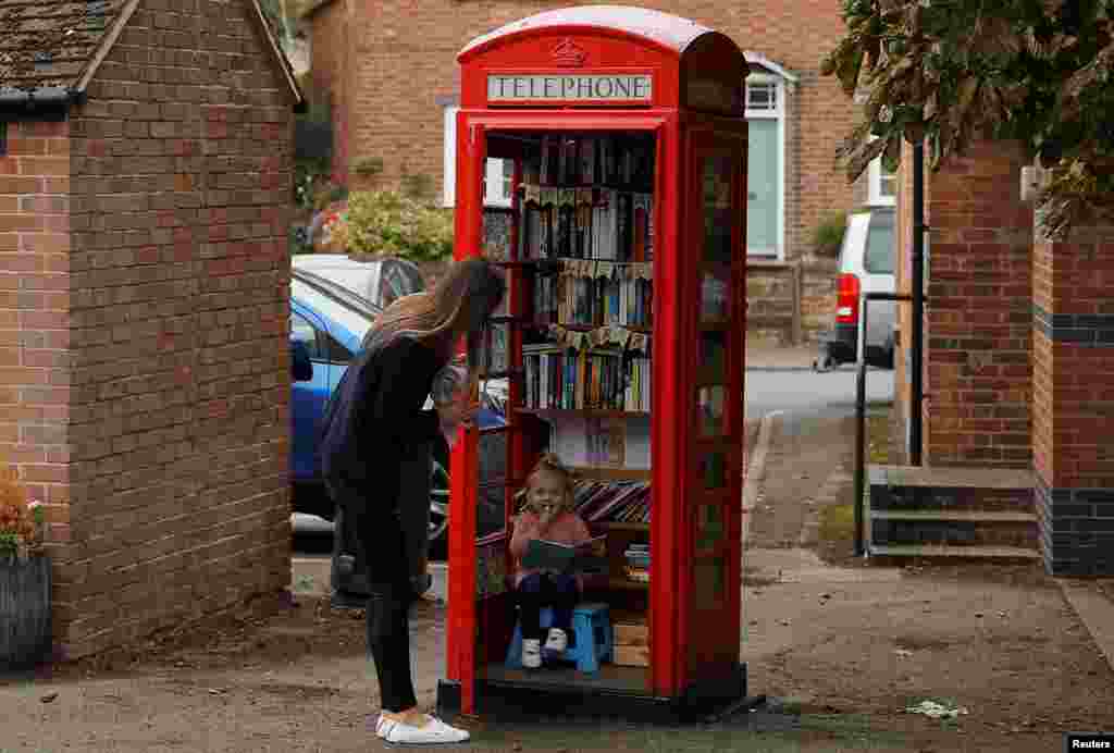 Aria Casey looks at books in a library inside a former British Telecom phone box in Long Clawson, Britain.