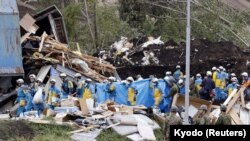 Police officers and members of the Japan Self-Defense Forces (JSDF) carry a missing person found from an area damaged by a landslide caused by an earthquake in Atsuma town, Hokkaido, northern Japan, in this photo taken by Kyodo, Sept. 8, 2018. 