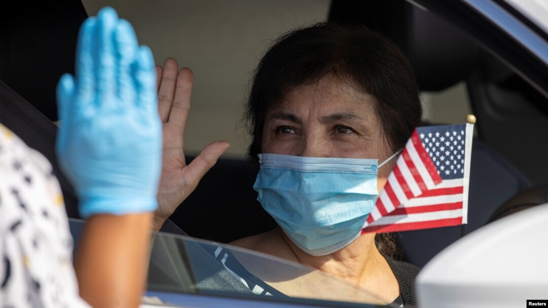 A U.S. immigration officer administers the oath as a swearing-in of newly naturalized United States citizens takes place in an empty parking lot during the outbreak of the coronavirus disease (COVID-19) in Santa Ana, California, July 29, 2020. 