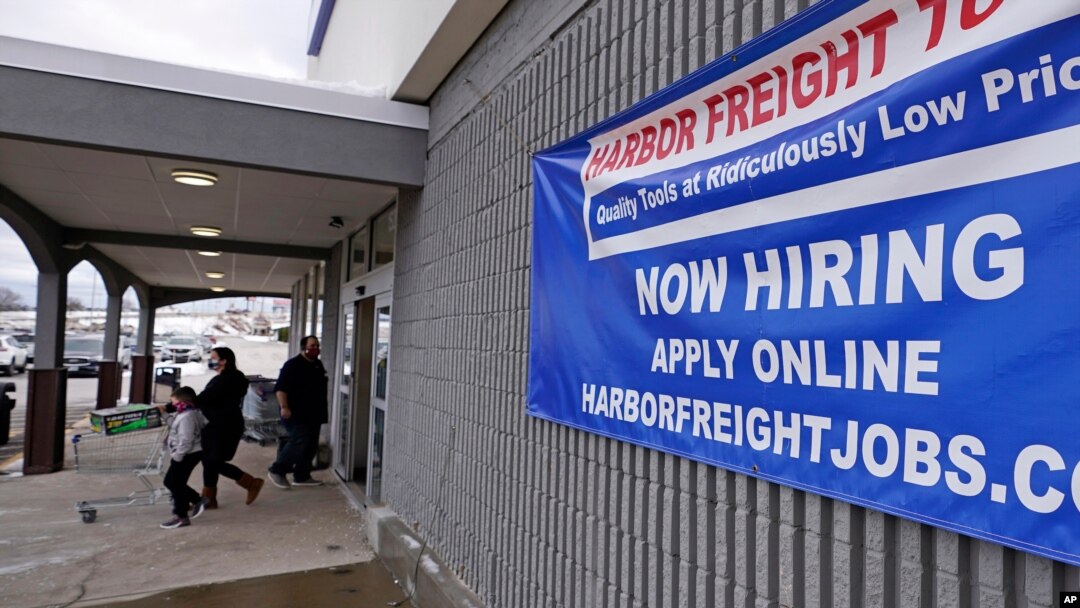 FILE - A 'Now Hiring' sign hangs on the front wall of a Harbor Freight Tools store in Manchester, New Hampshire, Dec. 10, 2020.