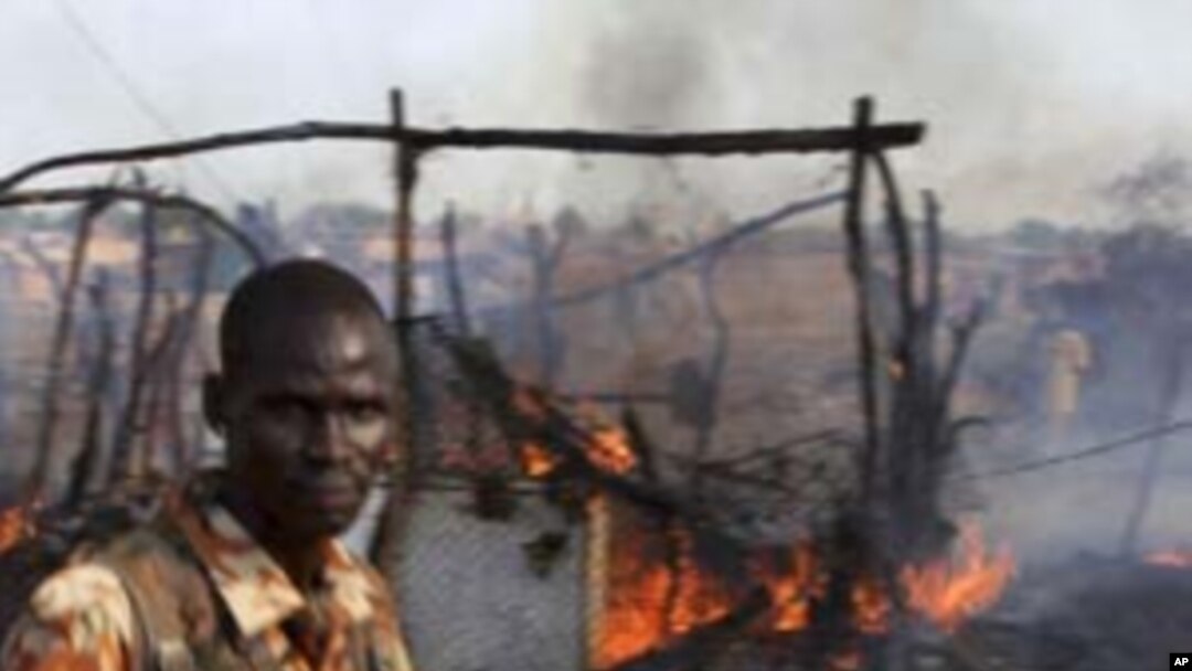A policeman walks past the smoldering remains of a market in Rubkona near Bentiu in South Sudan, April 23, 2012. 