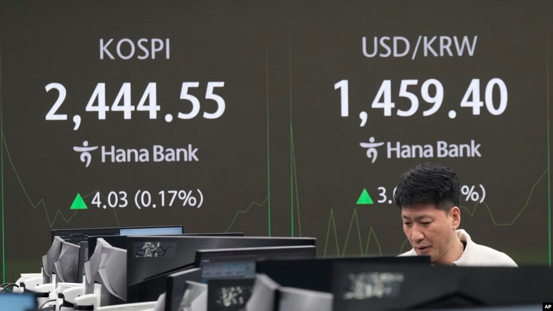 A currency trader watches monitors near a screen showing the Korea Composite Stock Price Index, left, and the foreign exchange rate between the U.S. dollar and the South Korean won at KEB Hana Bank headquarters in Seoul, South Korea, Dec. 26, 2024.