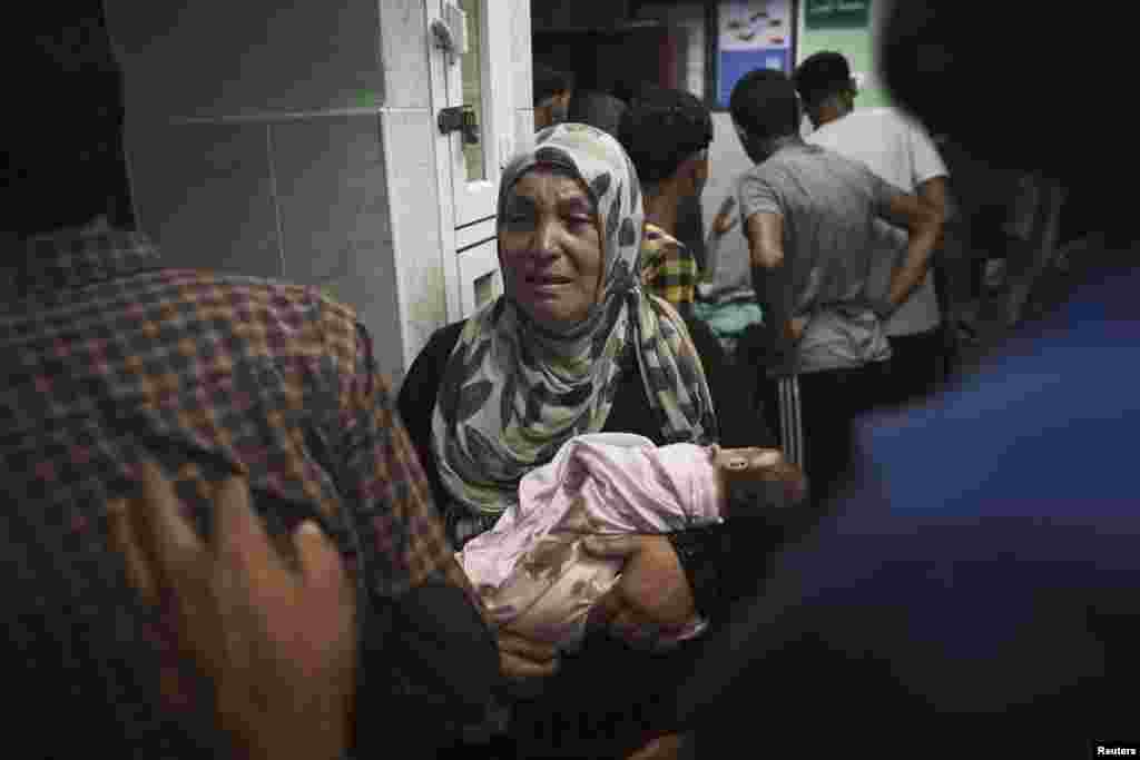 A Palestinian woman holds an infant, whom medics said was injured in an Israeli shelling at a U.N-run school sheltering Palestinian refugees, at a hospital in the northern Gaza Strip July 24, 2014.