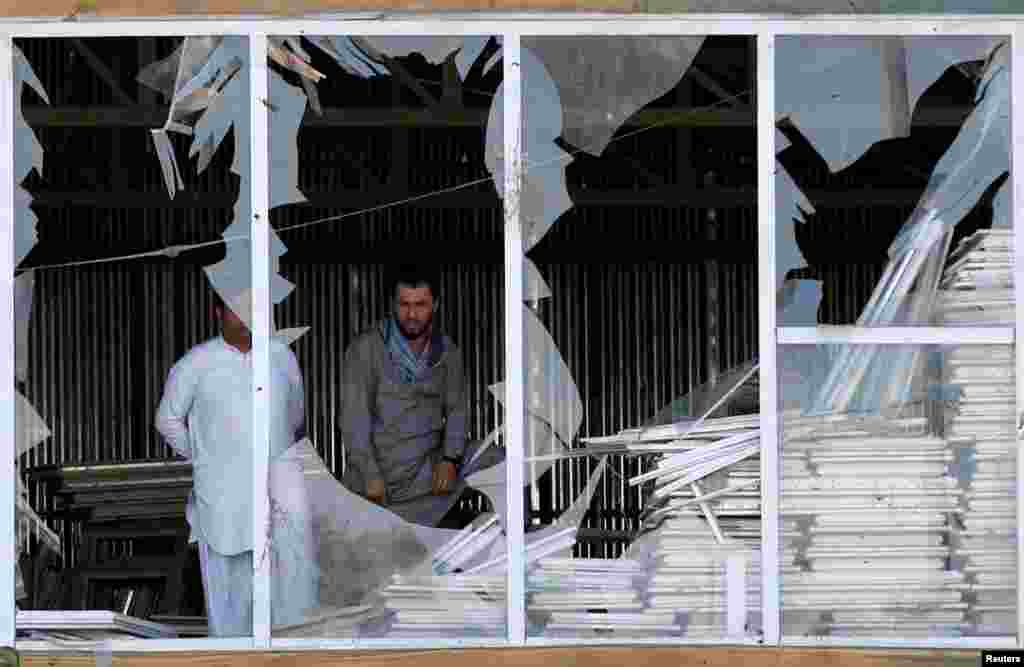 Afghan men look outside a broken window at the site of a suicide attack in Kabul, Afghanistan.
