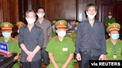 Freelance journalists of the Independent Journalists Association of Vietnam Pham Chi Dung, right, Le Huu Minh Tuan, center, and Nguyen Tuong Thuy stand during their trial Jan. 5, 2021.