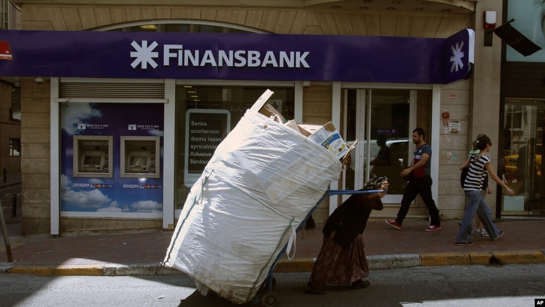 A scrap collector pulls her trolley in front of a Turkish bank in Istanbul, Tuesday, June 4, 2013. Turkey's stock market recovered slightly after plummeting amid nationwide unrest. On Monday the Borsa Istanbul 100 Index closed down 10.5 percent
