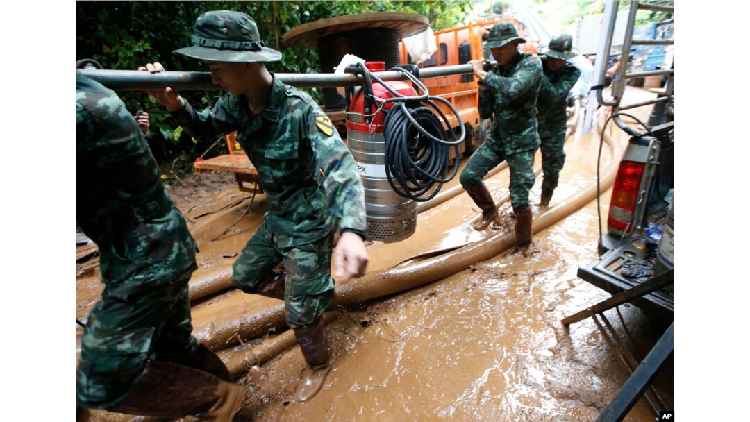 Soldiers carry a pump to help drain the rising floodwater in a cave where 12 boys and their soccer coach have been missing in Mae Sai, Chiang Rai province, northern Thailand, June 29, 2018.