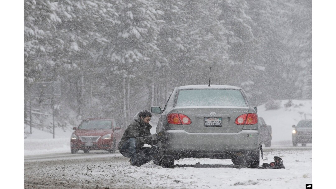 A motorist puts on snow chains near Echo Summit, California, Jan. 3, 2017.