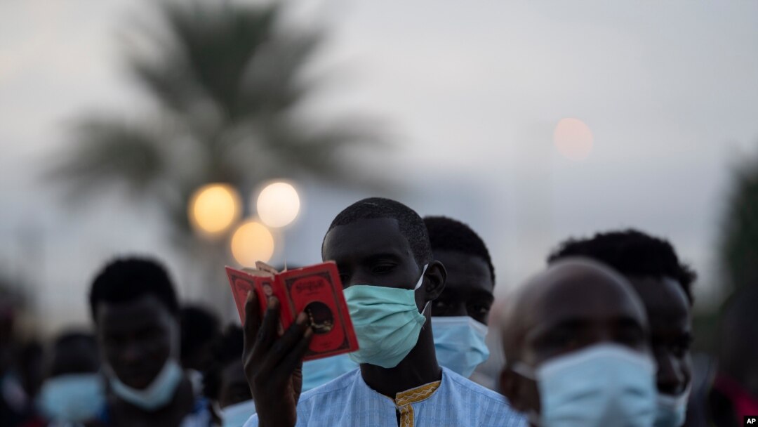a pilgrim from the Mouride Brotherhood, reads a book with poems written by Cheikh Amadou Bamba as he stands in line to enter at Grand Mosque of Touba in Senegal, Oct. 5, 2020.
