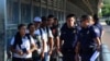 FILE - U.S. Customs and Border Patrol officers are seen with asylum-seekers on the international bridge between Laredo, Texas, and Nuevo Laredo, Mexico, July 10, 2019.