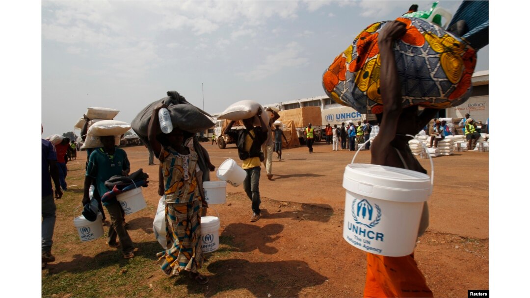 FILE - People displaced by the recent unrest, collect food distributed by aid agencies at an IDP camp at the Mpoko international airport of Bangui, Feb. 12, 2014.