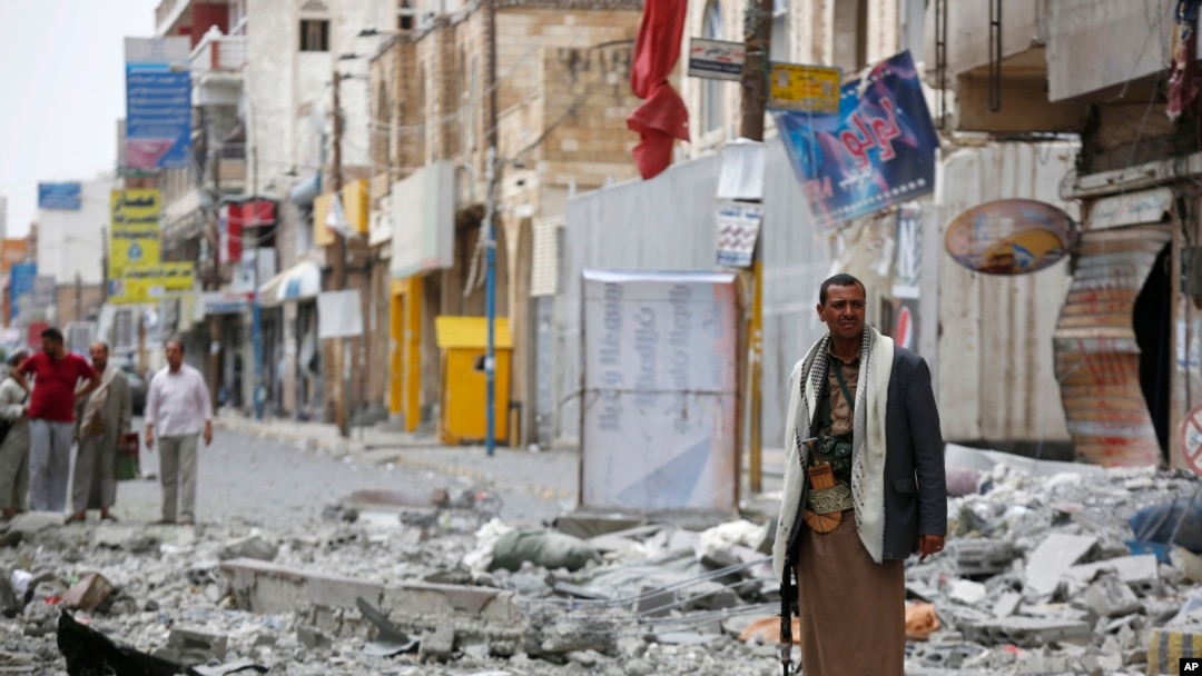FILE - A Shiite fighter known as a Houthi stands guard in front of buildings destroyed by a Saudi-led airstrike in Sana'a, Sept. 5, 2015. 
