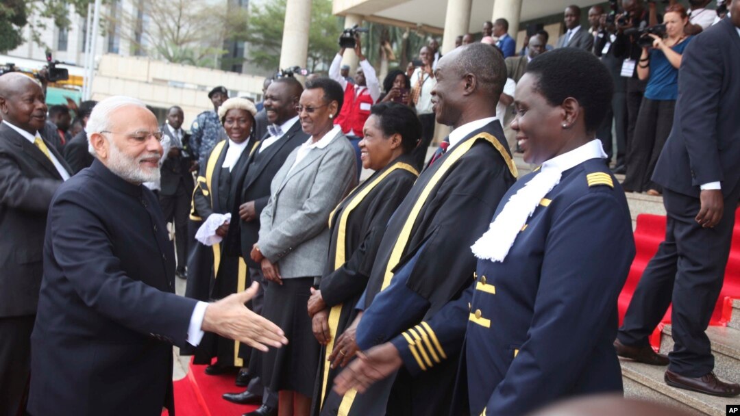 Indian Prime Minister Narendra Modi, second left, escorted by Uganda President Yoweri Museveni, left, meet members of Parliament in the Uganda capital of Kampala, July 25, 2018. 
