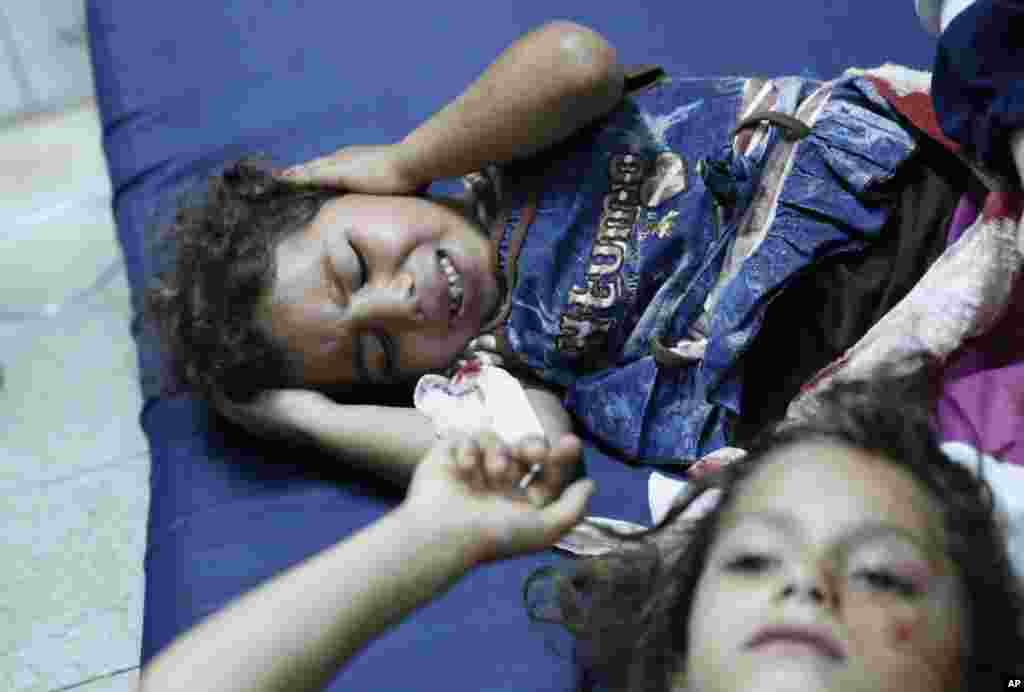 Palestinian children, wounded in an Israeli strike on a compound housing a U.N. school in Beit Hanoun, in the northern Gaza Strip, on the floor at the emergency room of the Kamal Adwan hospital in Beit Lahiya, July 24, 2014.