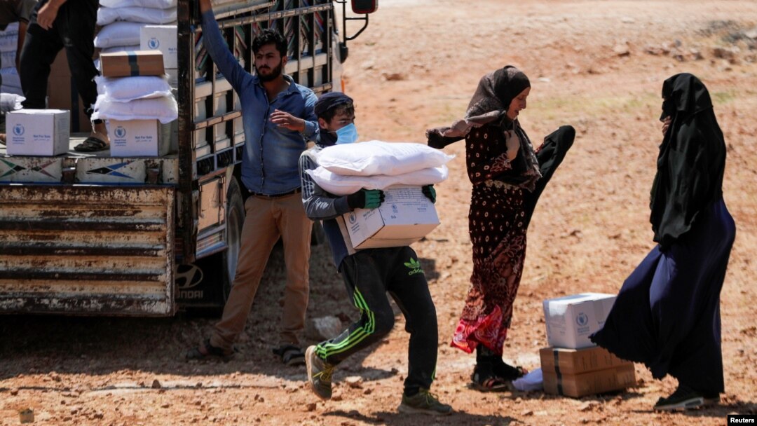 FILE - A worker holds bags and a box of humanitarian aid in the opposition-held Idlib, Syria June 9, 2021.