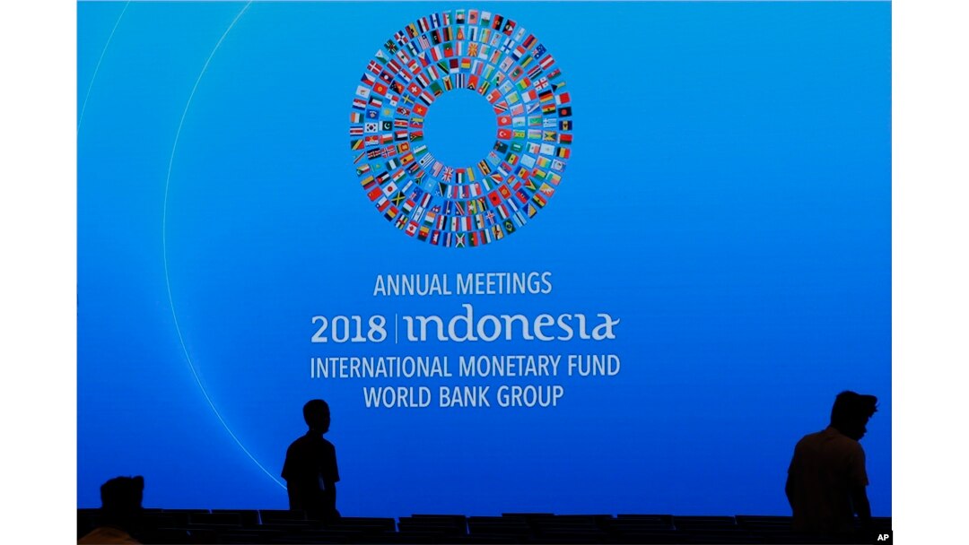 Workers pass by a banner of International Monetary Fund-World Bank annual meetings at a conference room in Bali, Indonesia, Oct. 8, 2018.