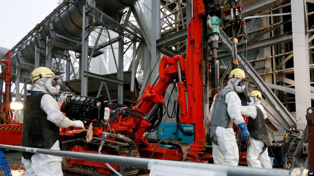 FILE - Workers drill pipes into the ground to be used to create a frozen underground wall to surround the crippled reactor buildings at Tokyo Electric Power Co.'s Fukushima Daiichi Nuclear Power Plant in Okuma, Fukushima Prefecture, northeast of Tokyo, Japan.