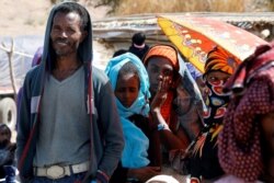 People wait in line for food aid from the WFP, at the Um Rakuba refugee camp which houses Ethiopians fleeing the fighting in the Tigray region, on the the border in Sudan, Dec. 3, 2020.