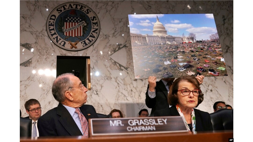 Senate Judiciary Committee Chair Sen. Chuck Grassley, R-Iowa, left, looks at a poster of 7,000 pairs of shoes that were displayed outside the Capitol Tuesday to represent victims of gun violence since the shootings at Sandy Hook Elementary School, as Ranking Member Sen. Dianne Feinstein, D-Calif., right, speaks during a committee hearing on the Parkland, Florida, school shootings and school safety, March 14, 2018, on Capitol Hill in Washington.